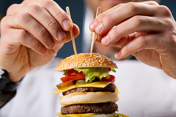 Hands using toothpicks to secure burger layers during food styling photography session