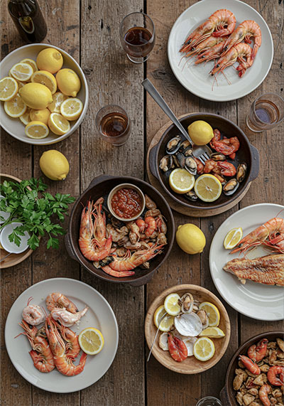 Before - rustic wooden table filled with freshly prepared seafood dishes, lemon slices, and herbs