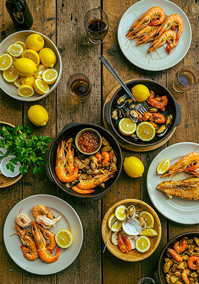 After - rustic wooden table filled with freshly prepared seafood dishes, lemon slices, and herbs