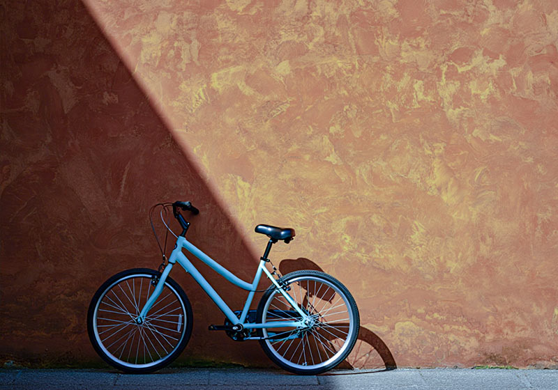 Before - bicycle leaning against a rustic burnt-orange wall