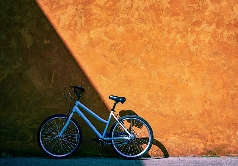 After - bicycle leaning against a rustic burnt-orange wall