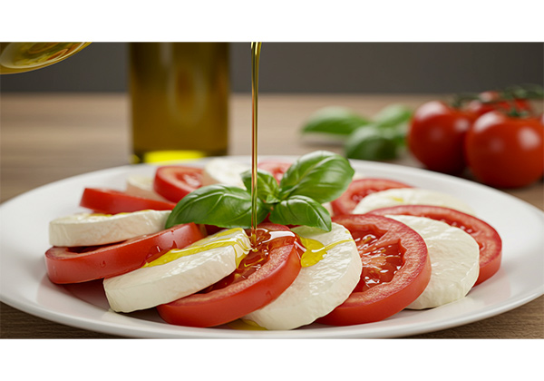 Action food photography showing olive oil being poured over caprese salad