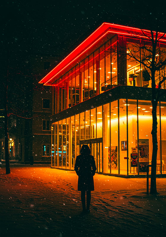 with preset - a person standing on a snowy sidewalk illuminated by neon light