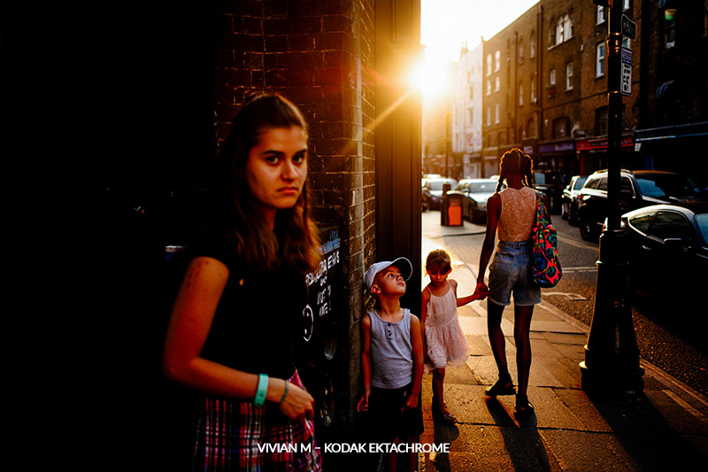 with Vivian M – Kodak Ektachrome preset - urban street scene during golden hour captures two women and two children standing on a sidewalk