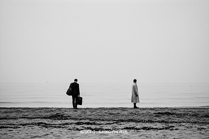 with Bruce G – Ilford FP4 Plus preset minimalist beach scene with two figures standing far apart, facing away from each
