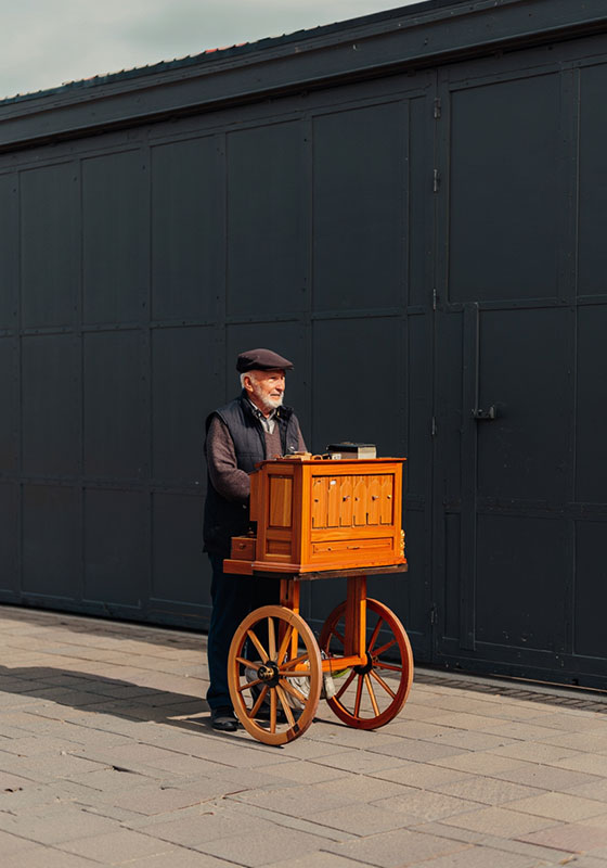 before - older man pushing his wooden barrel organ