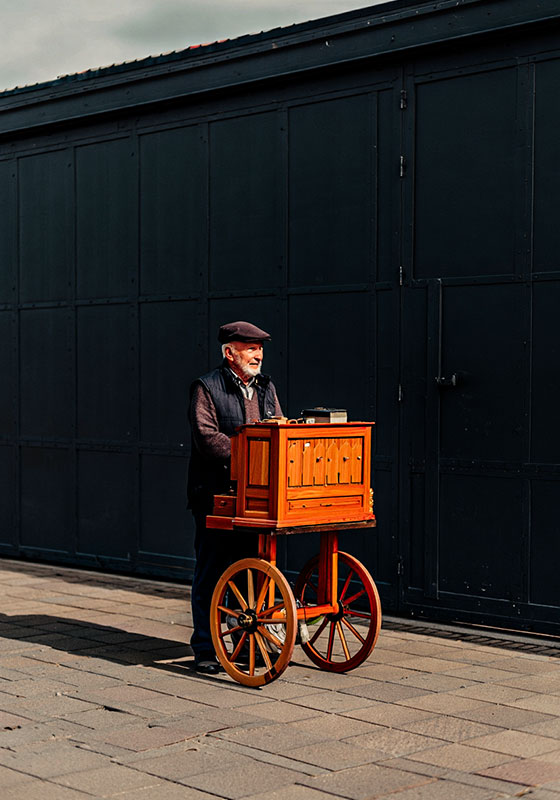 with preset - older man pushing his wooden barrel organ