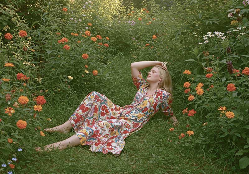 before - woman reclining in a lush garden filled with vibrant orange flowers and green foliage