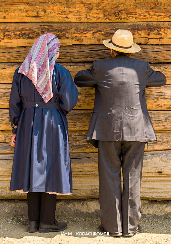 with Jay M – Kodachrome II preset - Two people stand with their backs to the camera against a weathered wooden wall