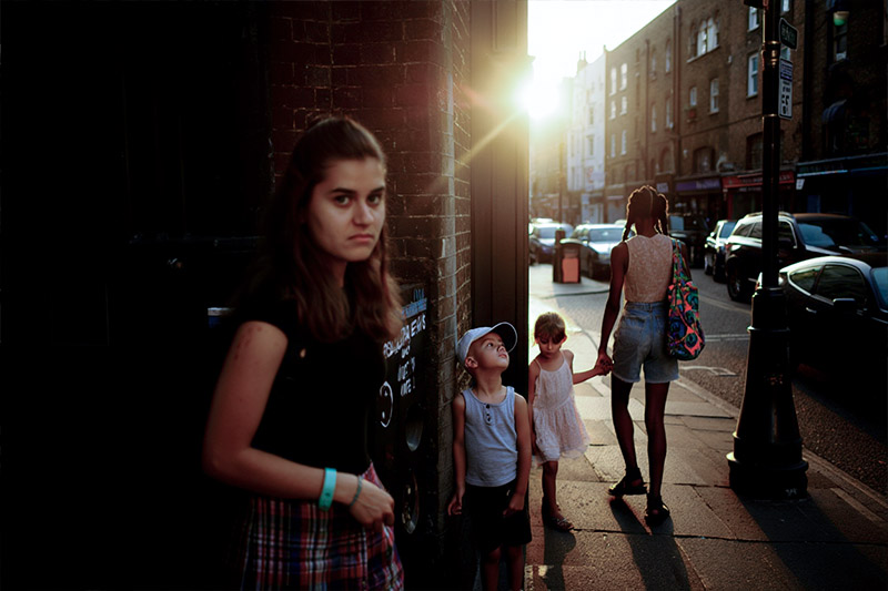 urban street scene during golden hour captures two women and two children standing on a sidewalk