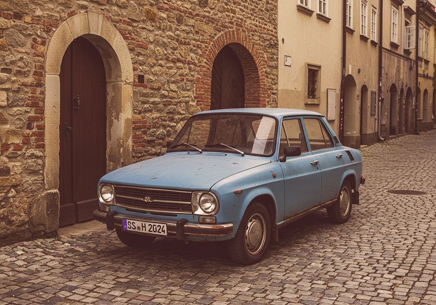 with preset - weathered blue Škoda car parked on a narrow cobblestone street