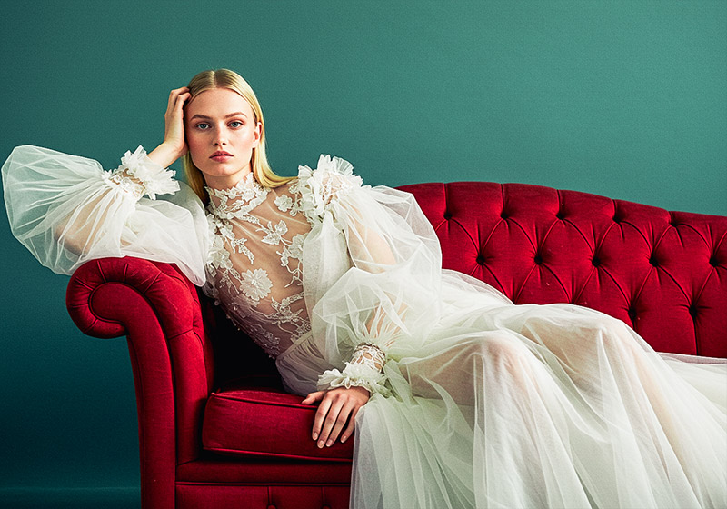 with preset - fashion photo of a poised model with sleek, straight blonde hair on a deep red tufted velvet sofa